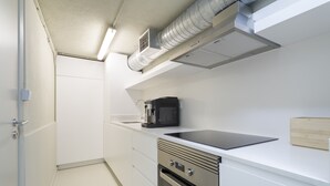 A modern kitchen with a built-in oven, microwave, and a black coffee maker on the countertop.