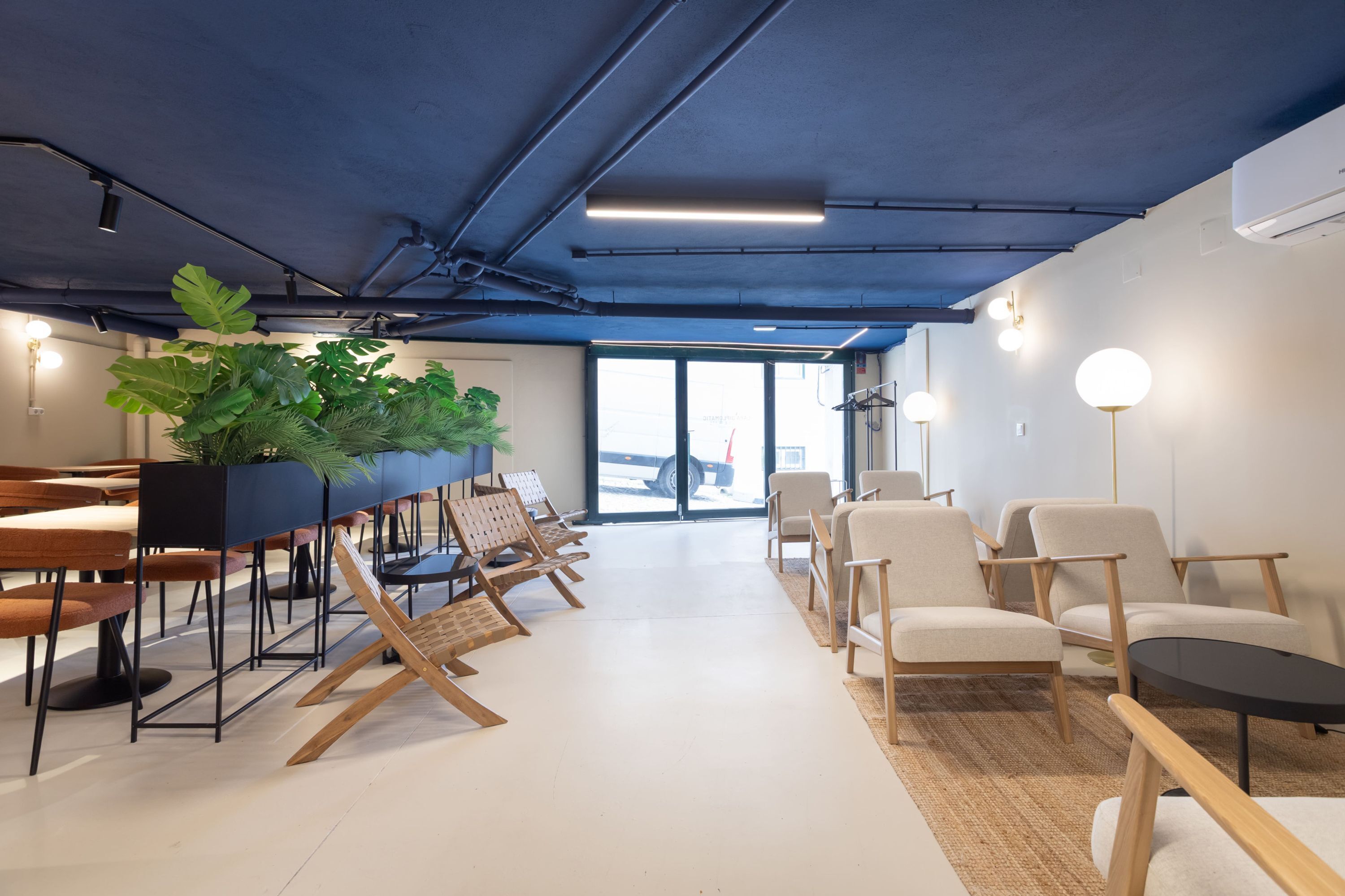 Ein modernes Interieur mit einem langen Tisch, Stühlen und einer großen Pflanze.
