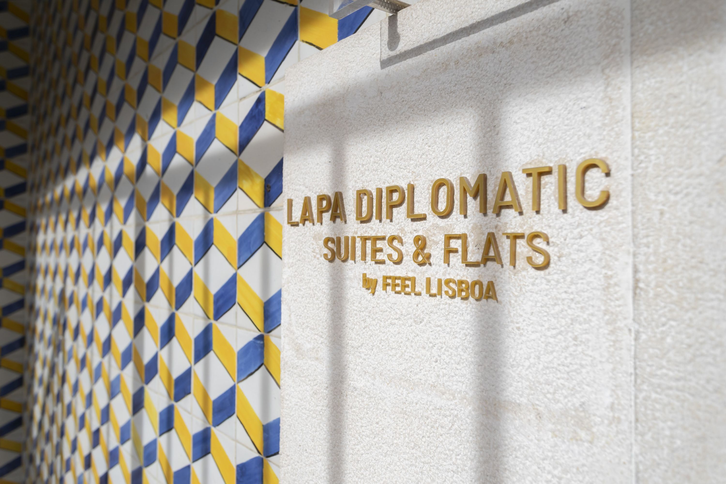 Een muur met een geometrisch patroon en tekst met de aanduiding 'LAPA DIPLOMATIC SUITES & FLATS by FEEL LISBOA'.