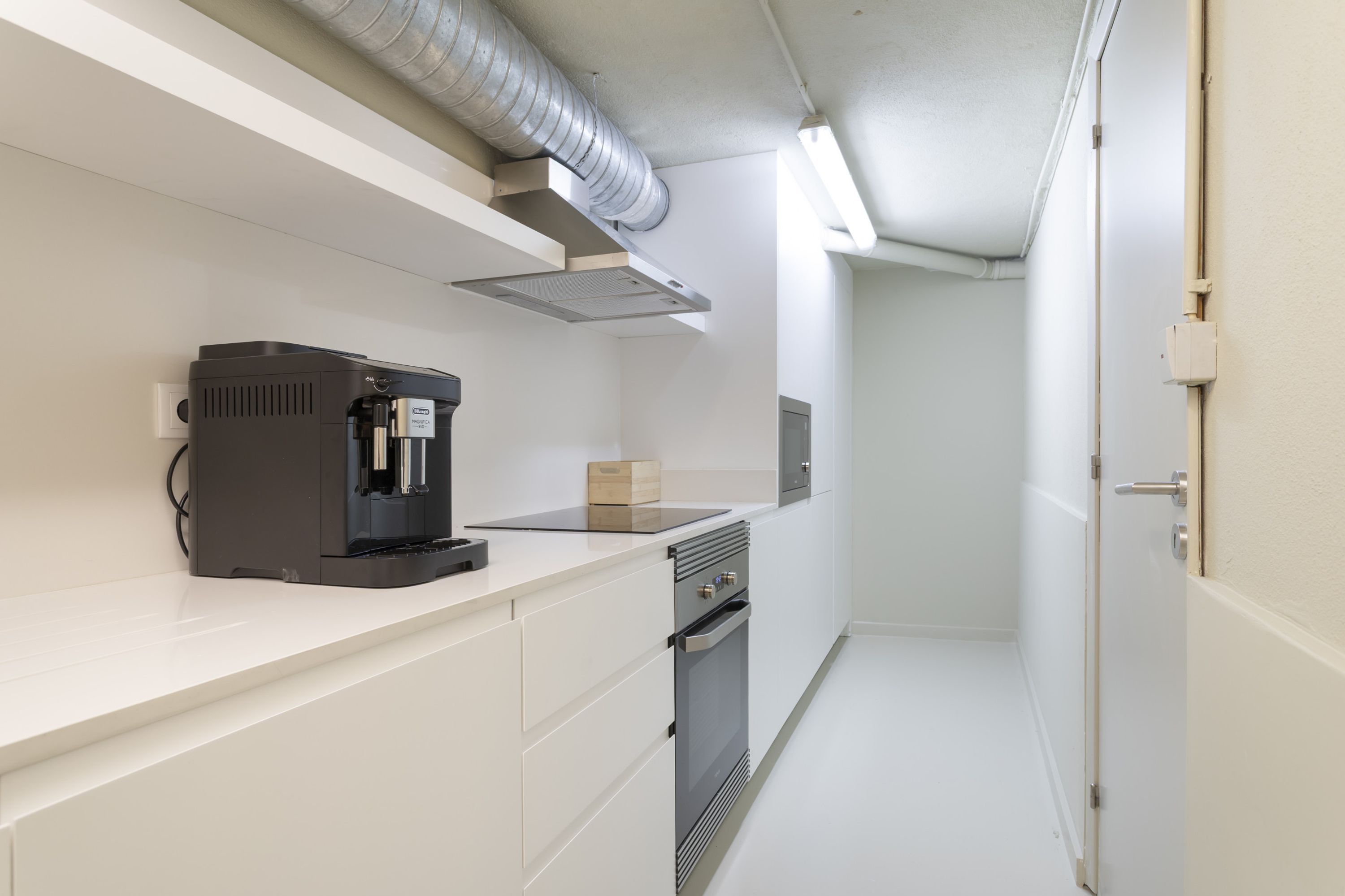 Een moderne keuken met een koffiezetapparaat, een magnetron en een inbouwoven.