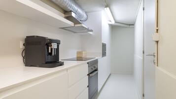 Een moderne keuken met een koffiezetapparaat, een magnetron en een inbouwoven.