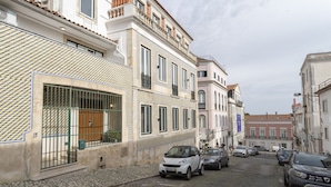A cobblestone street with parked cars and buildings with traditional architecture.