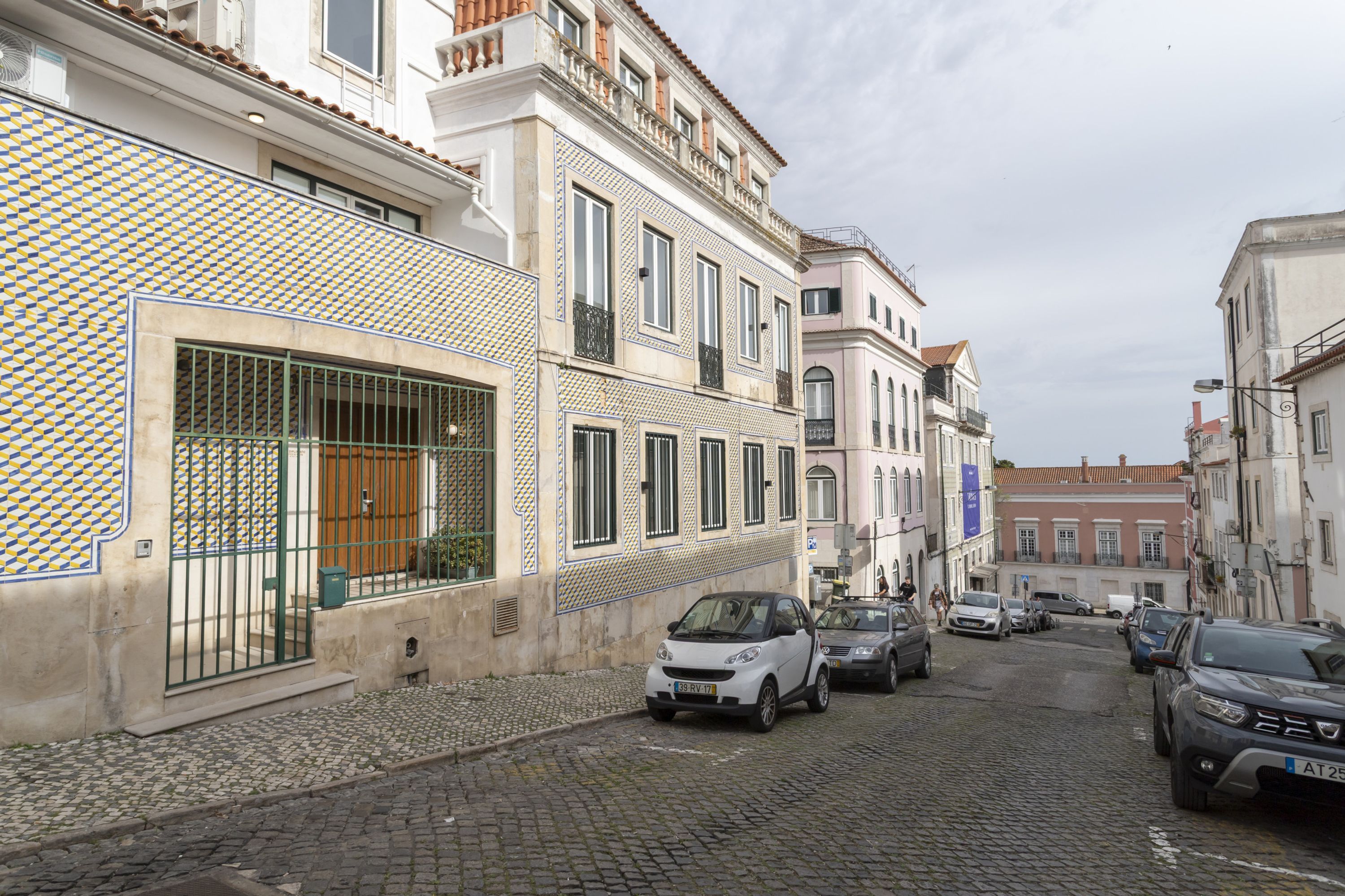 Eine Kopfsteinpflasterstraße mit geparkten Autos und Gebäuden im traditionellen Baustil.