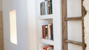 A bookshelf with books, a ladder, and a window.