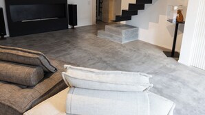 A modern living room with a grey sofa, a white sofa, and a black entertainment unit.