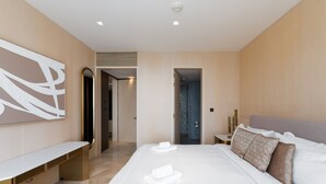 A modern hotel room with a large bed, a bench, and a wall-mounted artwork. - Spacious Beachside 2BR M at Five Palm Jumeirah (Dubai)