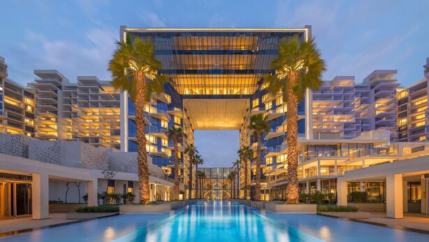 A modern hotel with a central swimming pool, multiple floors, and palm trees. - Spacious Beachside 2BR M at Five Palm Jumeirah (Dubai)
