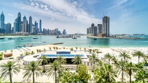 A coastal cityscape with a beachfront, palm trees, and modern high-rise buildings. - Spacious Beachside 2BR M at Five Palm Jumeirah (Dubai)