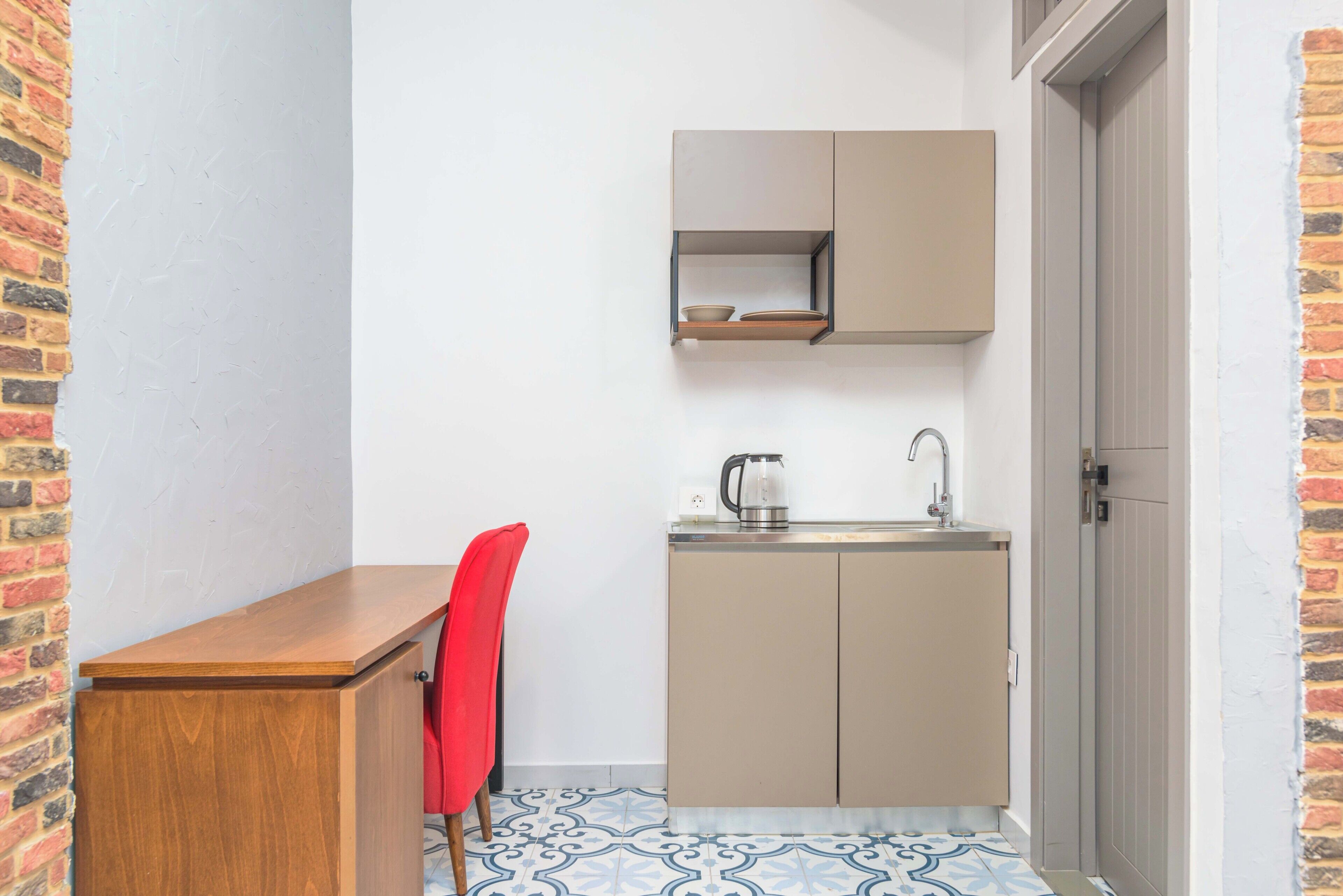 A compact kitchen with a wooden counter, a red chair, and a sink.