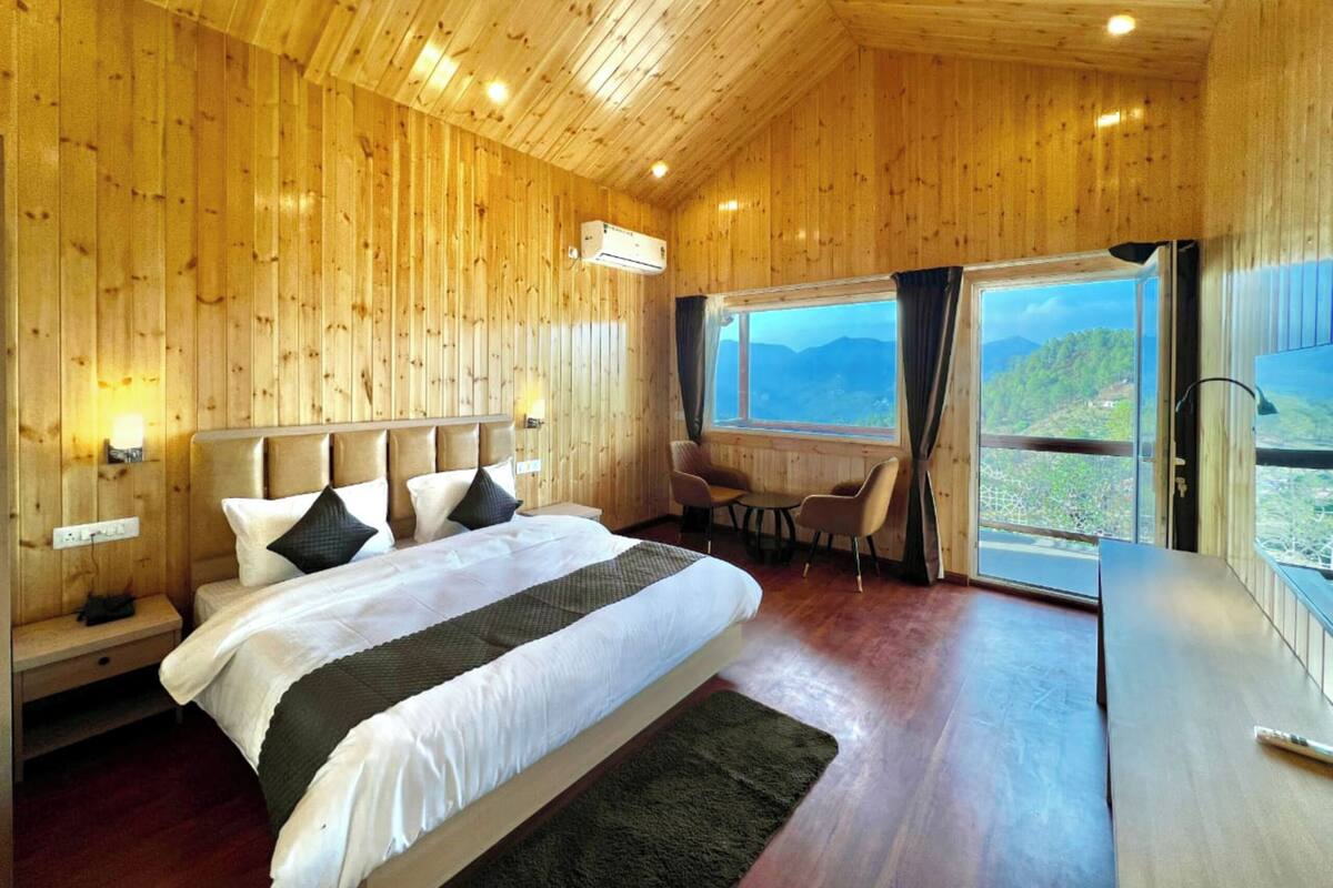 Un dormitorio con paneles de madera, una cama grande, un escritorio y vistas al exterior.