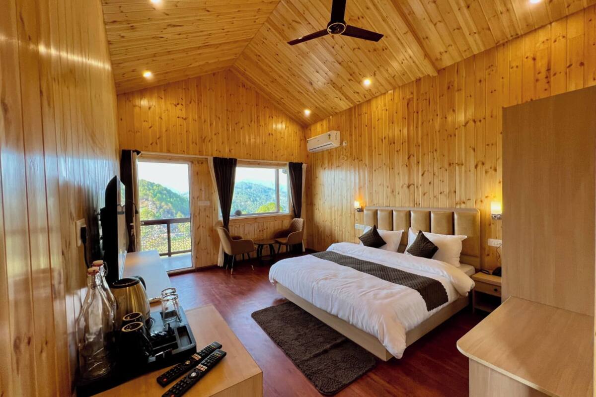 Una habitación con paneles de madera, una cama, un escritorio con cafetera y vistas al exterior.
