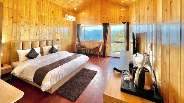 Un dormitorio de cabaña de madera con una cama, un escritorio, una silla y vistas a las montañas.