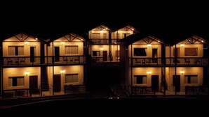 Un edificio de varios pisos con balcones y una escalera, iluminado en la noche.