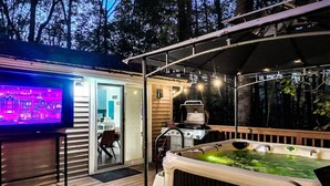 Una terraza con jacuzzi, parrilla y televisor que muestra una vista panorámica de la ciudad.