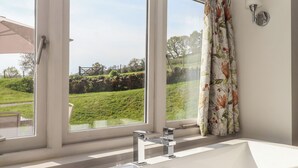 Une salle de bain dotée d’une grande fenêtre, d’une baignoire et d’un espace douche.