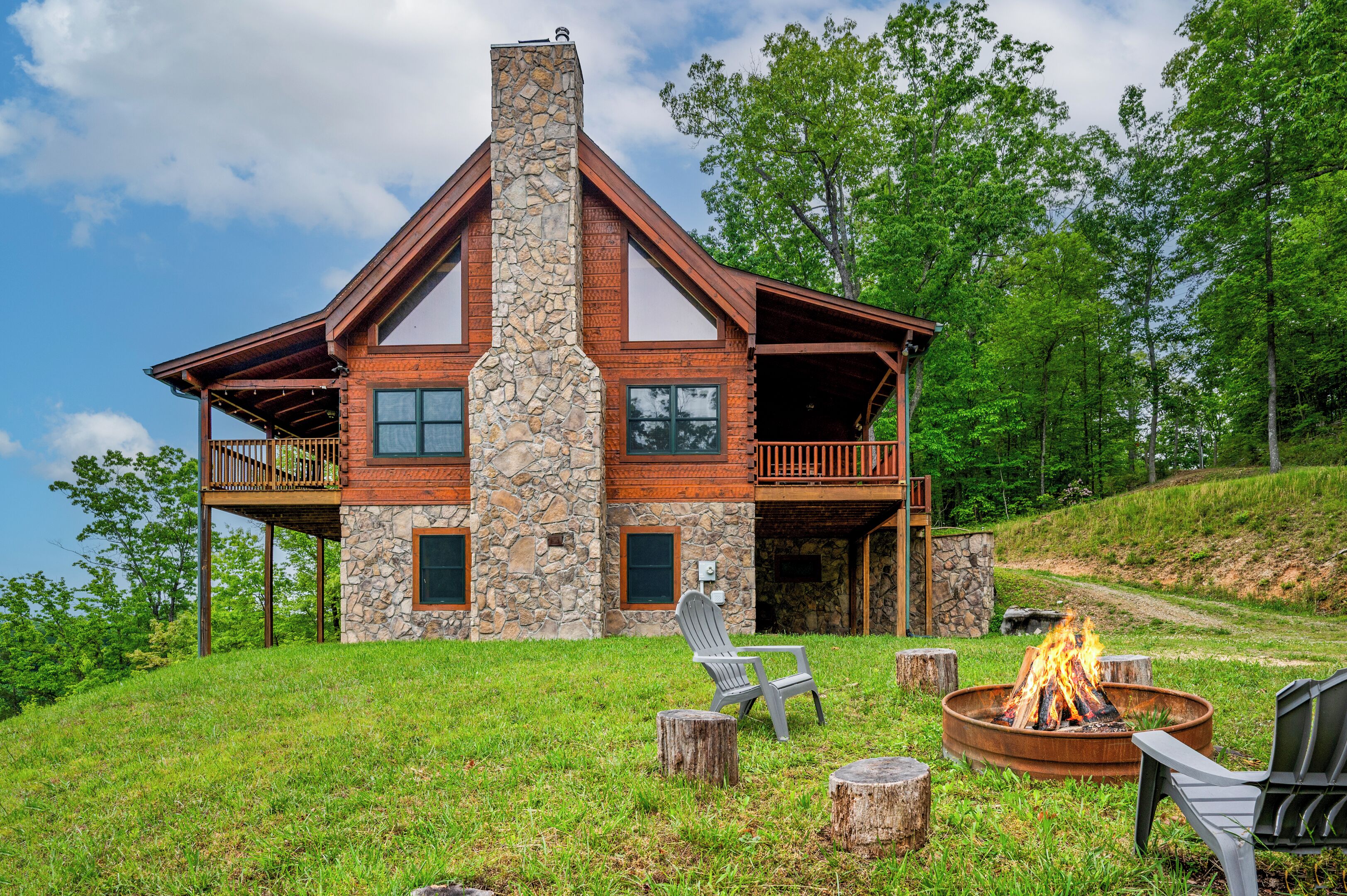 A large stone and wood cabin with a fire pit and outdoor seating.