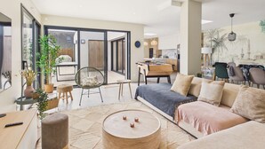 A modern living space with a sofa, coffee table, and a dining area with a foosball table.