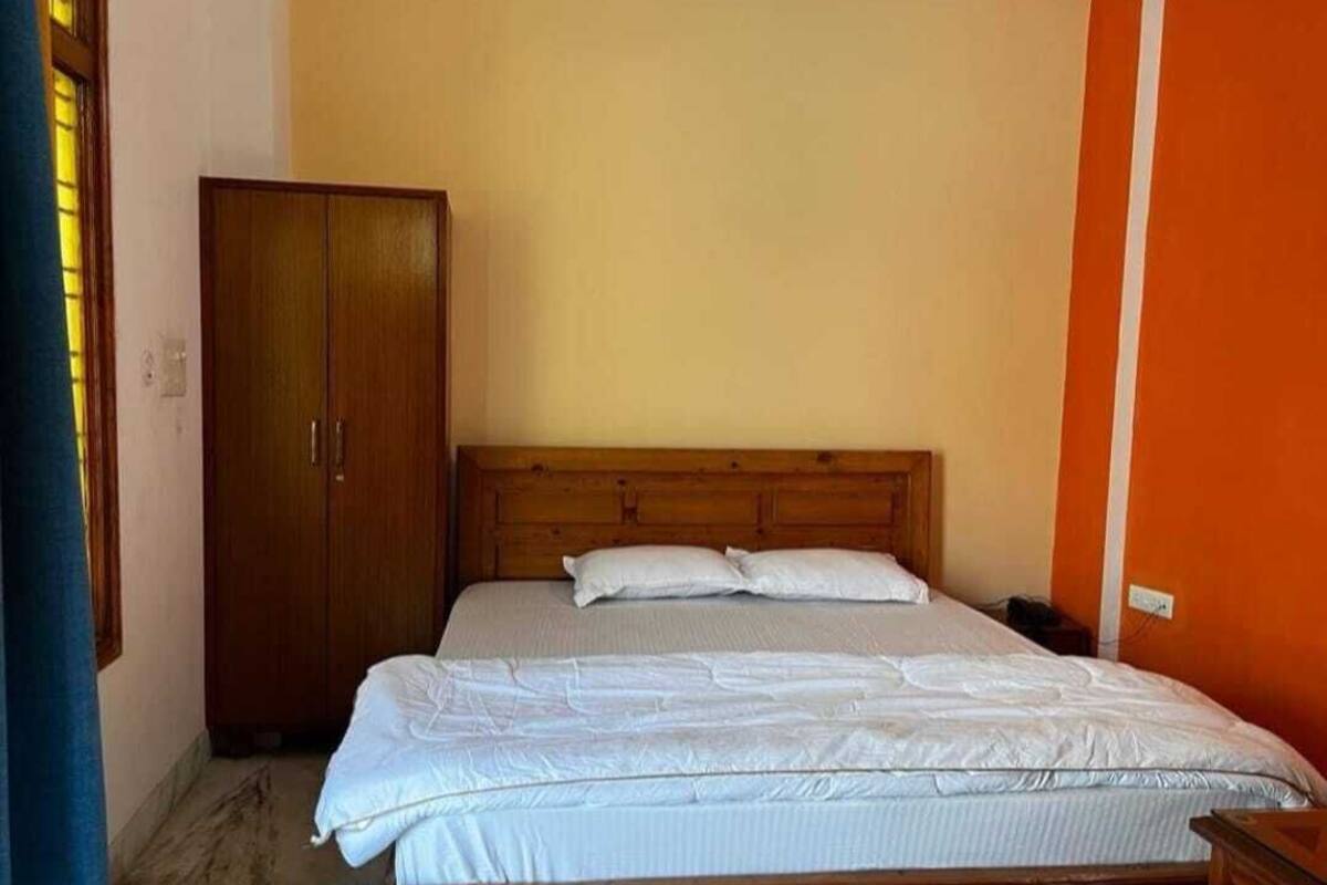 Ein Schlafzimmer mit einem hölzernen Bett, einem Kleiderschrank und einer schlichten Wand.