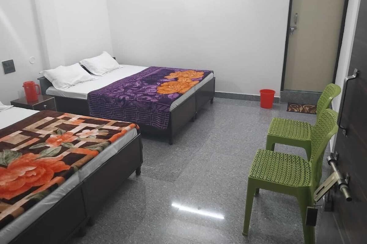 Ein Zimmer mit zwei Betten, einem grünen Sessel und einer Tür.