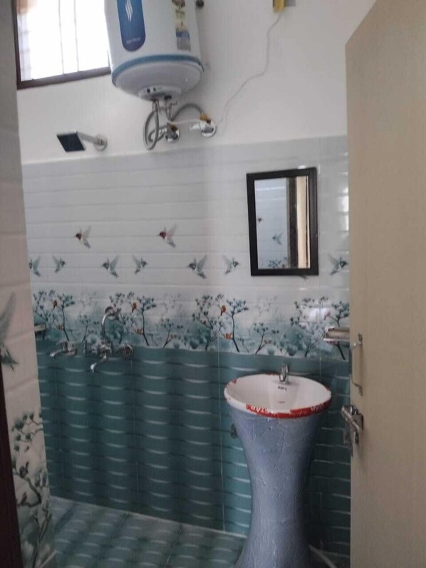 A bathroom with a pedestal sink, a mirror, and decorative wall tiles. - Rawat Residency (Rajgarhi)