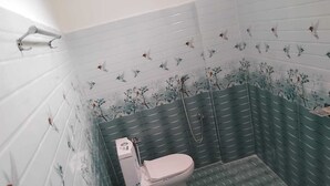 Ein Badezimmer mit Toilette, Dusche und einer Wand mit floralen Fliesenmustern.