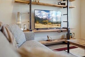 A modern living room with a mounted TV, wooden shelves, and a cozy sofa.