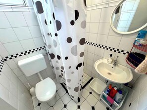 Un baño con inodoro, lavamanos y cortina de ducha a lunares.