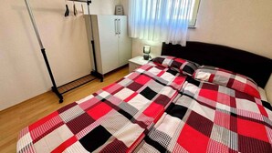 Un dormitorio con cama, armario, radiador y ventana con cortinas.