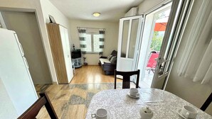 Comedor con una mesa preparada para dos, cocina al fondo y vista al exterior a través de una puerta corrediza.