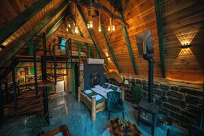 Un intérieur chaleureux de chalet en bois avec une chambre à coucher en mezzanine, une décoration rustique et une cheminée en pierre.