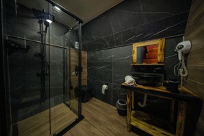 Une salle de bain moderne avec une douche à parois de verre, un meuble-lavabo en bois et un sèche-cheveux fixé au mur.