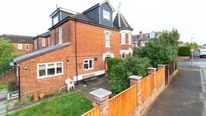 A two-story brick house with a front garden, a wooden fence, and a visible driveway. - Thornbury Guest House Room 2 (Southampton)