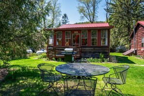 Een chalet met een rood dak, een terras en een barbecueplaats.