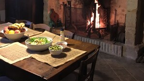 Una mesa de comedor con comida, una chimenea y una lámpara colgante.