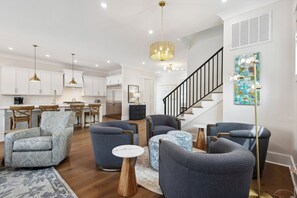 Ein modernes Wohnzimmer mit Treppe, Essbereich und Küche.