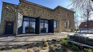 A stone building with large glass doors, a parked car, and a bicycle.