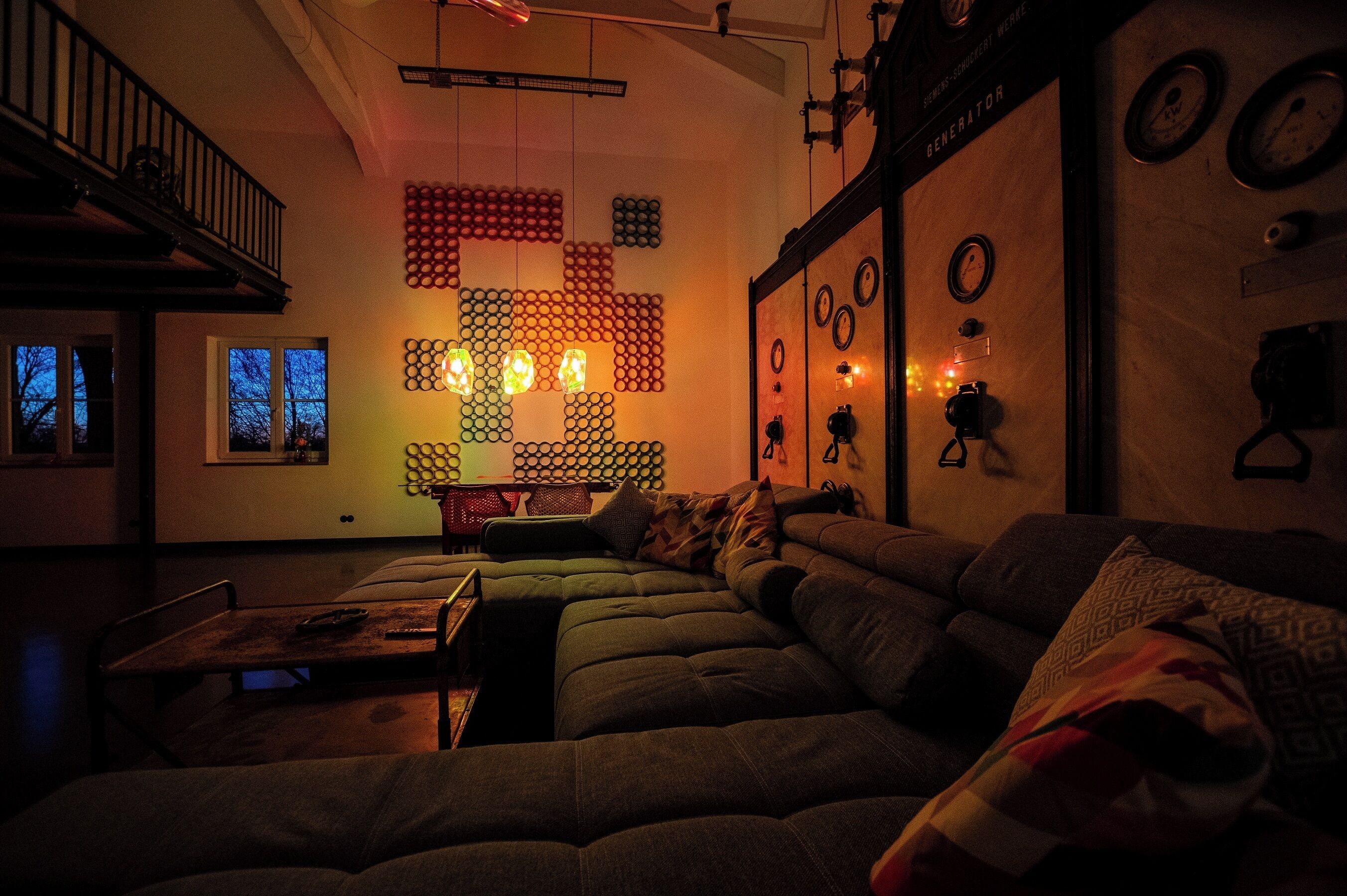 Ein gemütliches Wohnzimmer mit einer Eckcouch, einem Couchtisch aus Holz und einer Wandkunstinstallation aus runden Objekten.