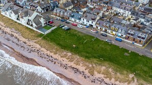 An aerial view of a coastal residential area with houses, a beach, and a road. - Creel Cottage 4 - Stunning Beach Front Access & Views - Free Parking - Garden (Arbroath)