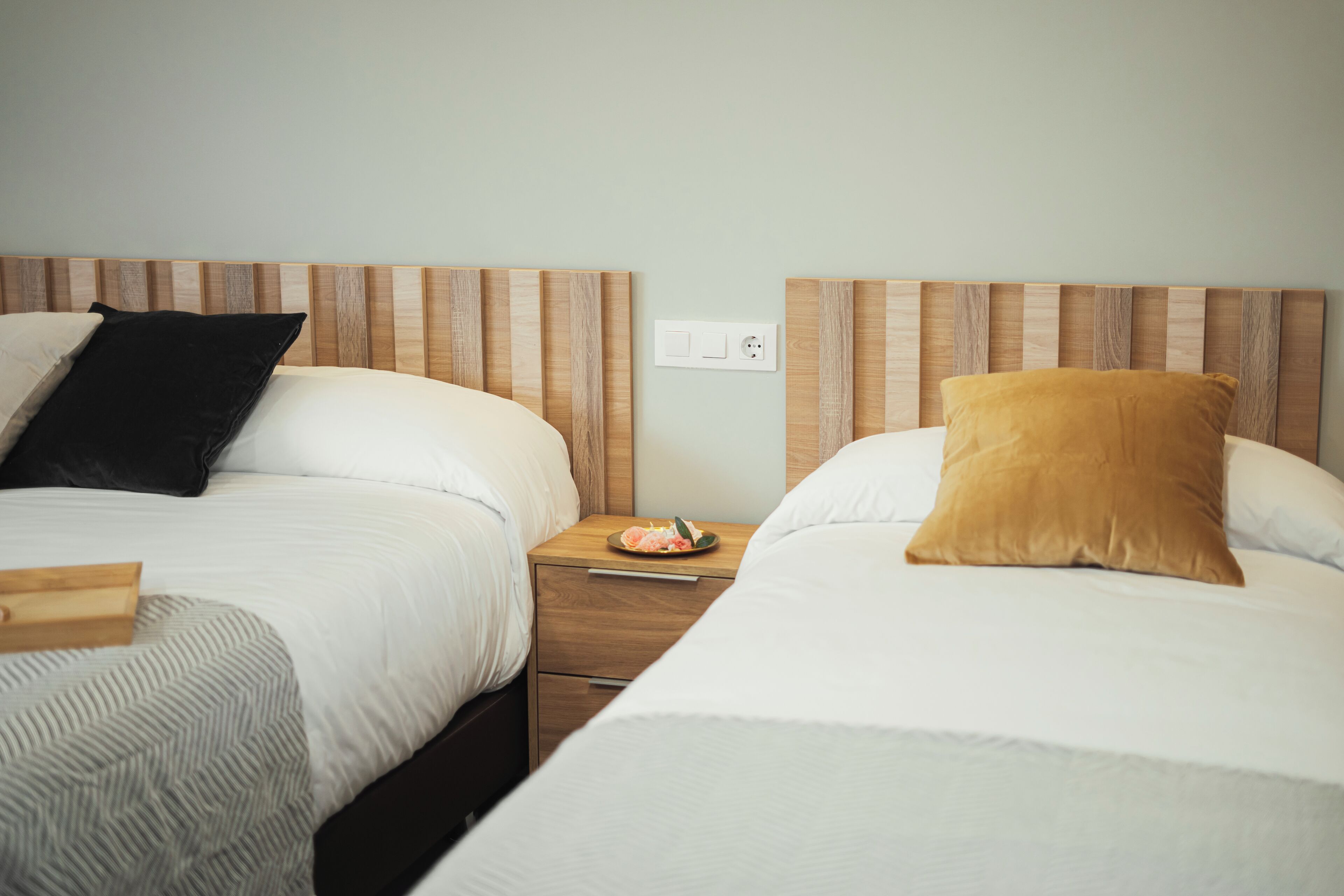 A hotel room with two beds, each with a wooden headboard, a nightstand between them, and a small table with a plate of food.