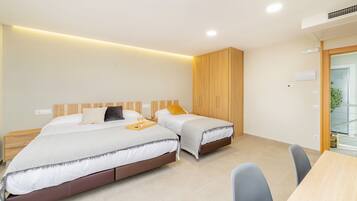 Una habitación de hotel moderna con dos camas, un armario de madera, un escritorio y una silla.