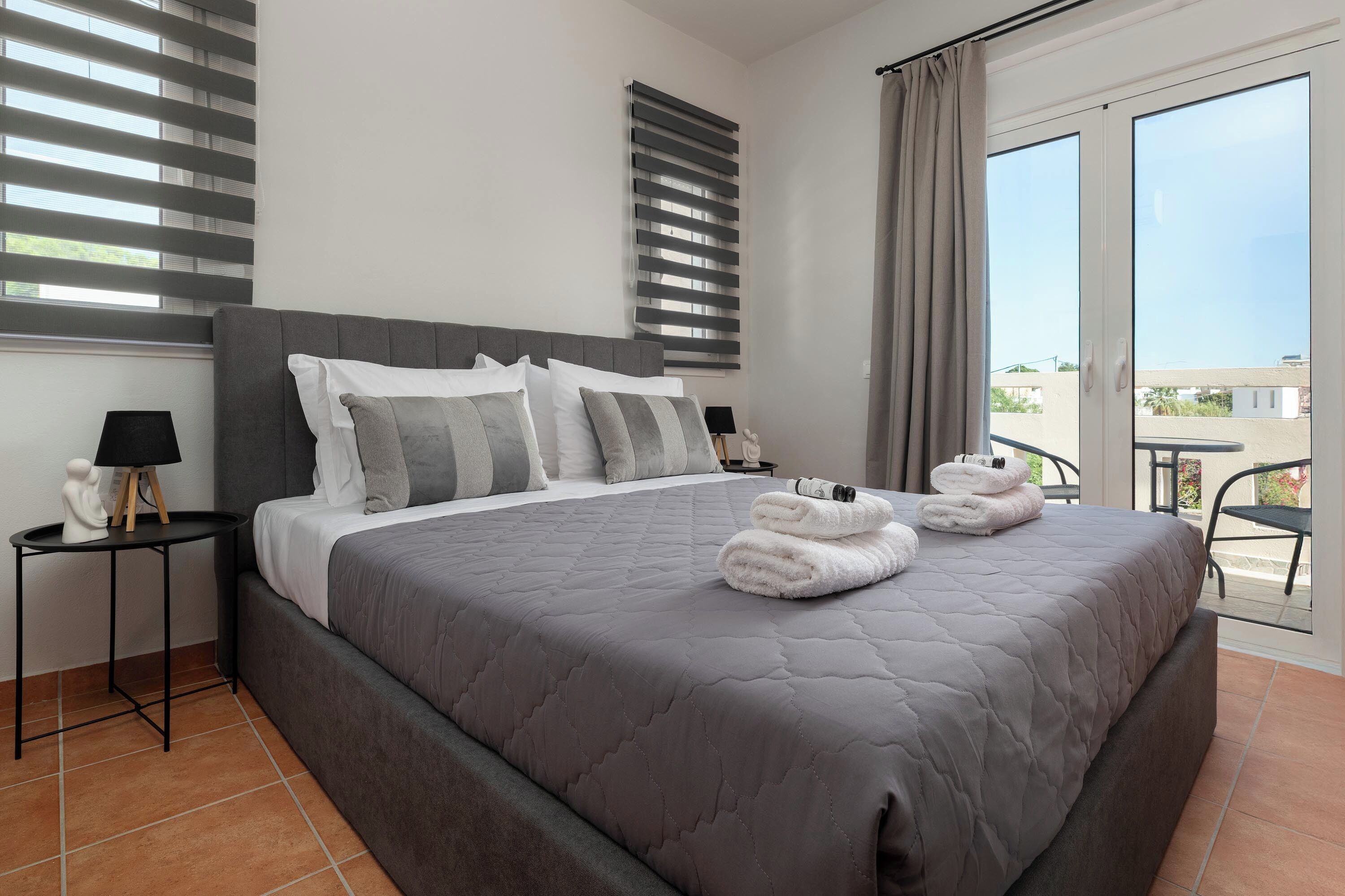 Una camera d'albergo con un letto grande, un comodino, una lampada e vista sull'esterno.