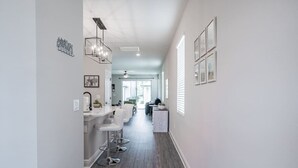 Eine moderne Küche mit weißen Arbeitsplatten, einer Bar inklusive Barhocker und Blick in den Essbereich.