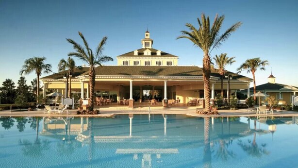 Ein großes Hotel mit Pool, Palmen und einer überdachten Terrasse.
