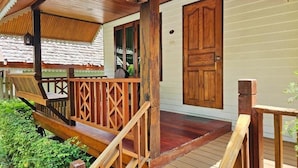 A wooden deck with a railing, a door, and a small table. - Siri Lagoona Resort & Pool Villa (Bang Lamung)