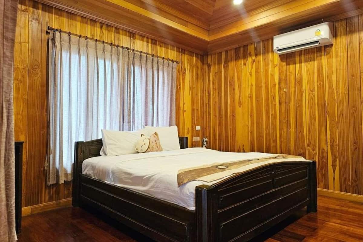 A wooden-paneled room with a bed, curtains, and an air conditioning unit.