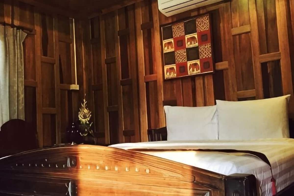 A wooden-paneled room with a bed, a chair, and a wall-mounted shelf.