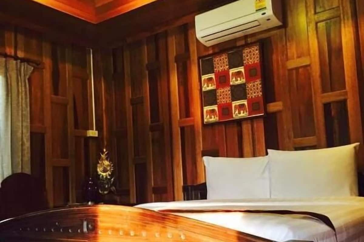 A wooden-paneled room with a bed, an air conditioning unit, and a decorative wall panel.