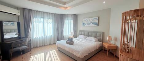 A modern bedroom with a bed, bedside tables, a desk, and a chair.