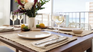 A dining table set with plates, cutlery, and glasses, with a vase of flowers and lemons on the table.