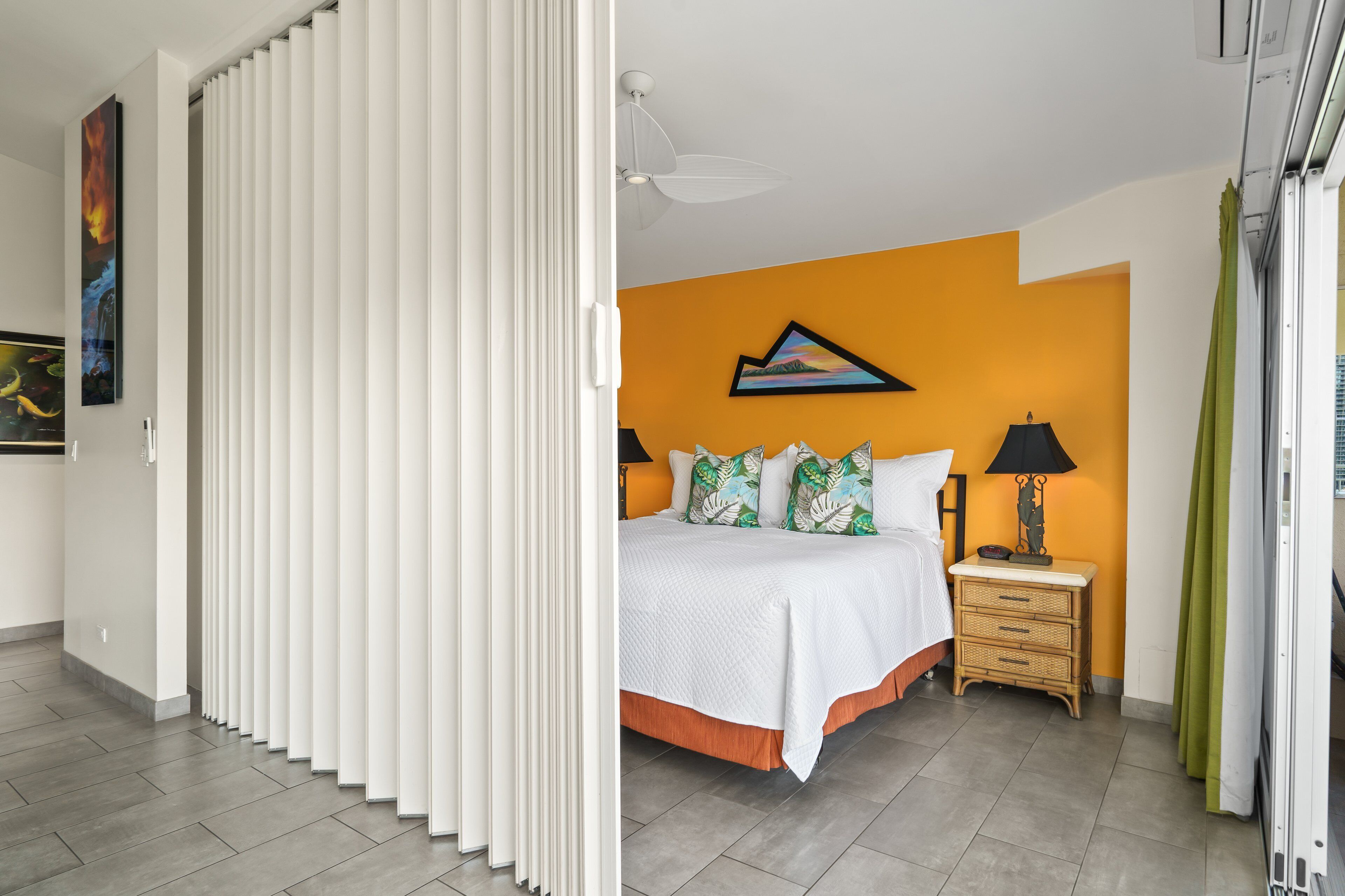 A bedroom with a bed, a nightstand, a lamp, and a painting on the wall.
